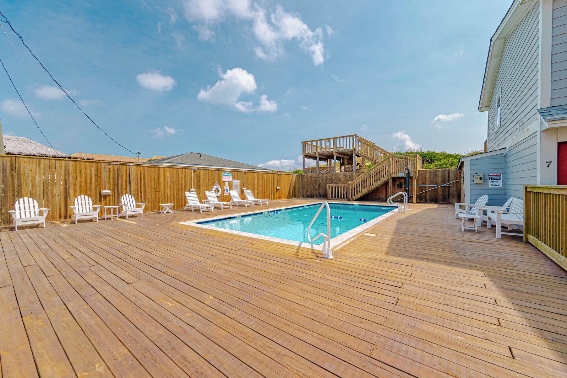 Une terrasse en bois avec une piscine, des chaises longues et une autre terrasse en bois avec une piscine.