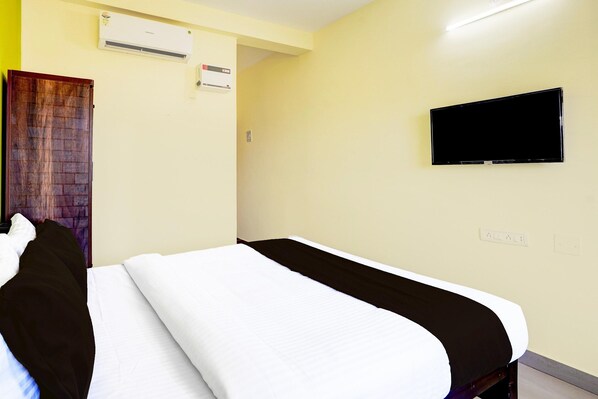 Une chambre d’hôtel équipée d’un lit, d’un téléviseur fixé au mur et d’un appareil de climatisation.