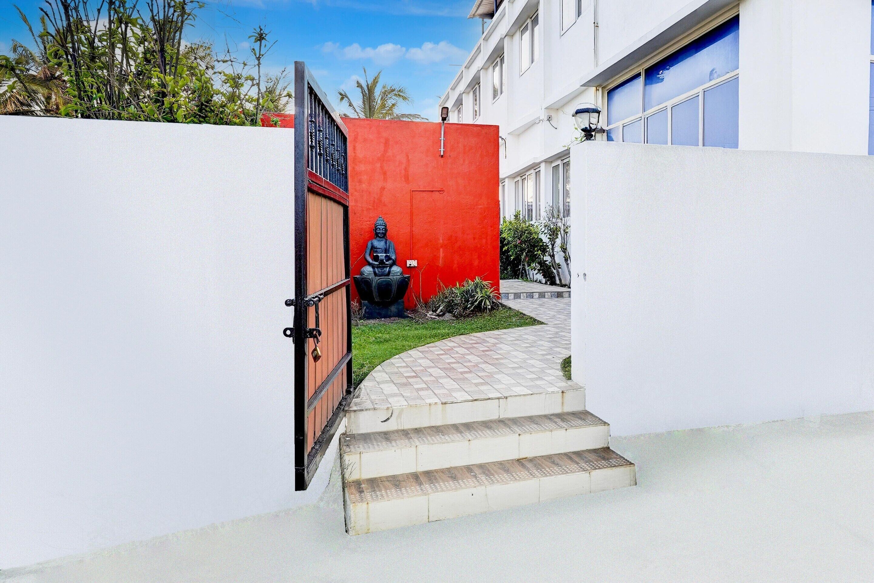 Ein Gebäudeeingang mit roter Wand, Buddha-Statue und blauer Garagentür.