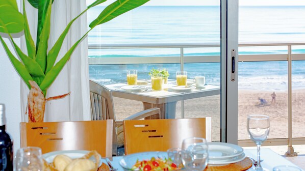 A table with breakfast items, a glass of water, and a view of the beach. - Apartamentos Turisticos Rent Guardamar (Guardamar del Segura)