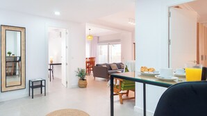 A modern living room with a dining area, a large mirror, and a view into the kitchen. - Apartamento Sirena (Guardamar del Segura)