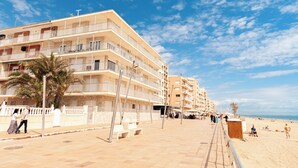 A multi-story hotel with balconies, a beachside location, and a clear sky. - Apartamento Sirena (Guardamar del Segura)