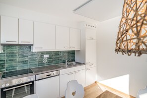 A modern kitchen with white cabinets, a green backsplash, and a built-in dishwasher.