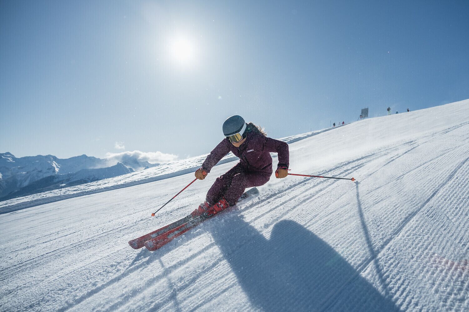 A skier on a snowy slope with mountains in the background.