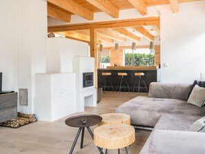 A modern living room with a grey sofa, two round wooden side tables, a TV, and a fireplace.