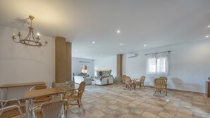 Un vaste espace de vie comprenant une table à manger, des chaises, un lustre et une cheminée en pierre.