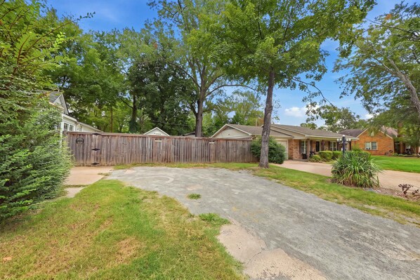 A residential area with a fenced backyard, a driveway, and houses with brick exteriors.