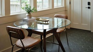 A room with a glass table surrounded by leather chairs, large windows, and a door with a keypad lock.
