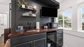 A modern kitchen with a dark countertop, black cabinets, a built-in microwave, and a window with a view of the outdoors.