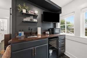 Una cocina moderna con encimera oscura, armarios negros, microondas integrado y una ventana con vistas al exterior.