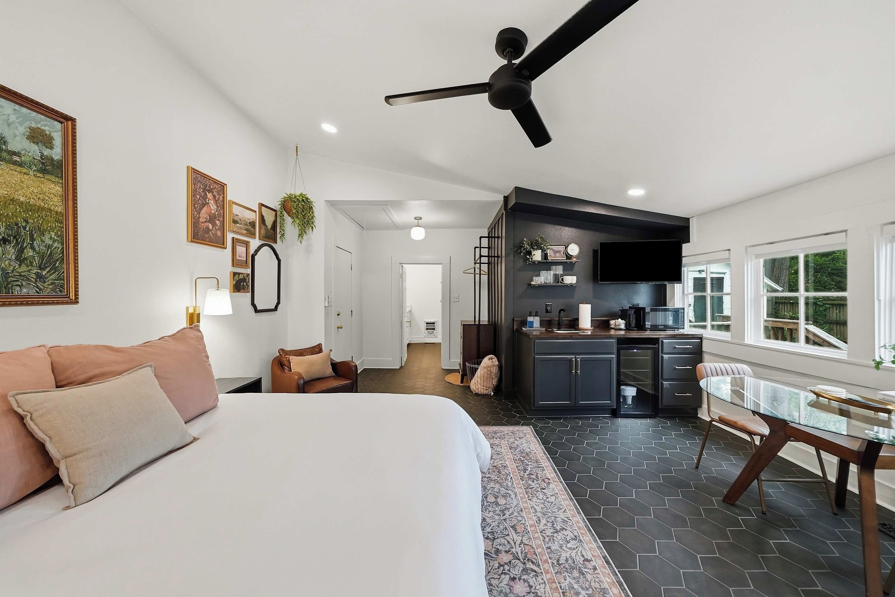 Un dormitorio moderno con una cama grande, una zona de estar con sofá y una cocina con mesa de comedor.