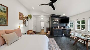 Un dormitorio moderno con una cama grande, una zona de estar con sofá y una cocina con mesa de comedor.