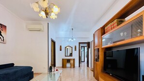A living room with a sofa, a glass coffee table, a TV, and a wooden entertainment unit. - YourHome - Letizia's House (Sorrento)