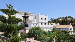 Un edificio residencial con fachada blanca, varias ventanas y un farol en primer plano.