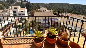 Un balcón con plantas en macetas, vistas a edificios residenciales y cielo despejado.