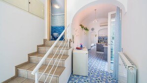 A staircase with a white railing leading to a room with a blue patterned floor. - YourHome - Lorena Maria House Positano (Positano)