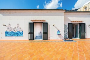 A building with a tiled floor, two open doors, and a mural of a coastal scene. - YourHome - Lorena Maria House Positano (Positano)