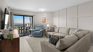 Ein modernes Wohnzimmer mit einer Couch, einem Sessel und Blick ins Freie.