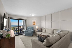A modern living room with a sofa, armchair, and a view to the outside. - Coastal Retreat @ Sea Mark Tower (Myrtle Beach)