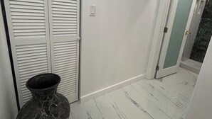 Ein Flur mit einer weißen Tür, einem Thermostat und einer Vase auf dem Boden.