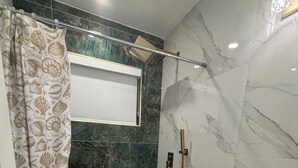 Ein Badezimmer mit Dusche, Toilette, Waschbecken und Marmorwänden.