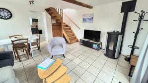 Un salon avec un escalier en bois, un téléviseur, une cheminée et un coin repas.