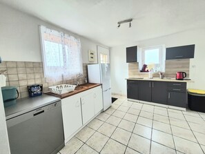 Eine kompakte Küche mit Geschirrspüler, Spüle, Kühlschrank und Kaffeemaschine.