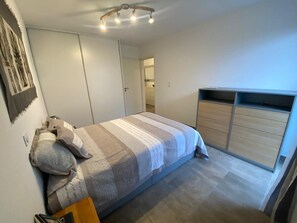 A bedroom with a bed, a wardrobe, and a door leading to another room.