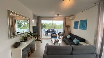 A modern living room with a grey sofa, a coffee table, and a dining area with a table and chairs.