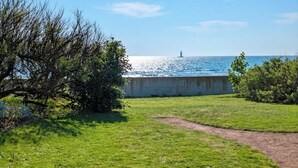 Eine Rasenfläche mit einer Betonmauer und einem Weg, der zu einem Gewässer führt.