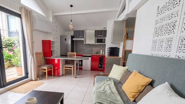 A compact living space with a dining area, kitchenette, and a sofa with cushions. - Quiet little house in Bayonne (Bayonne)