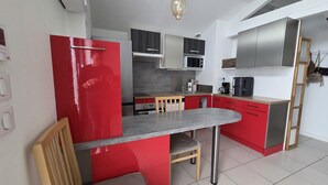 A compact kitchen with red cabinetry, a small dining area, and a microwave. - Quiet little house in Bayonne (Bayonne)