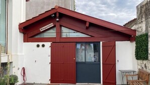 A building with a red roof, a dark blue door, and a small table and bench outside. - Quiet little house in Bayonne (Bayonne)