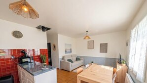 Eine kompakte Küche mit Essbereich, einer Couch und einem Fenster mit Vorhängen.