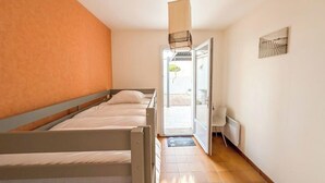 Ein Schlafzimmer mit zwei Betten, einer Schiebetür zu einem Balkon, einem Heizkörper und einer Pendelleuchte.