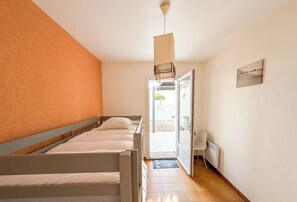 A bedroom with two beds, a sliding door to a balcony, a radiator, and a hanging light fixture. - Bright house with terrace in La Terrière (La Tranche-sur-Mer)