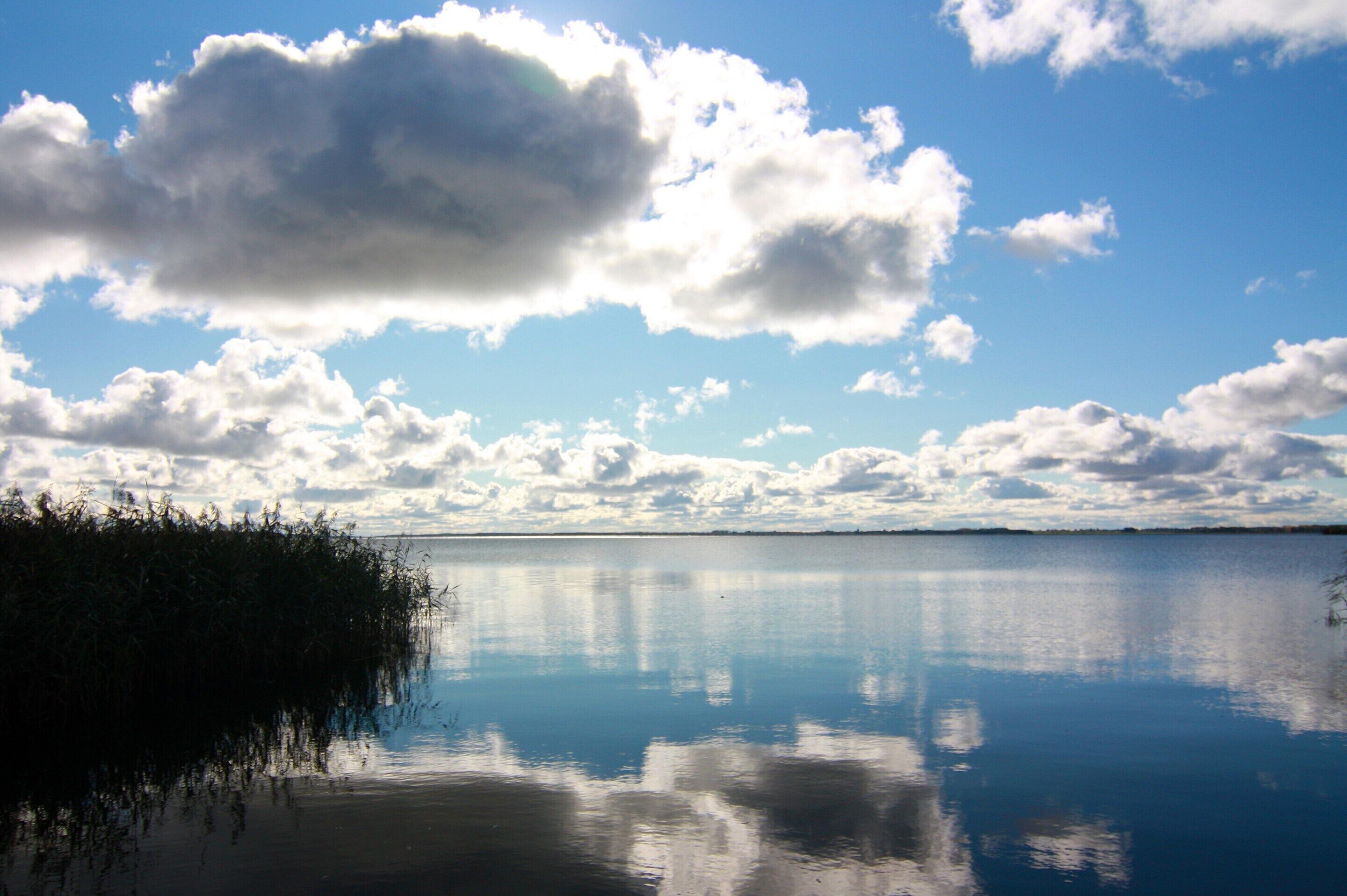 A calm lake with a clear sky and clouds.