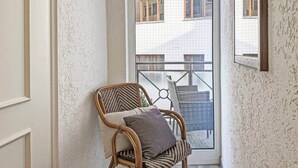 A corner room with a wicker chair, a window with a view of buildings, and a textured wall.