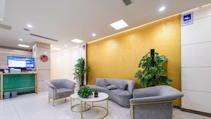 A reception area with a sofa, chairs, a small table, a plant, and a computer monitor. - Jinjiang Inn Beijing Yizhuang Economic & Technical (Beijing)