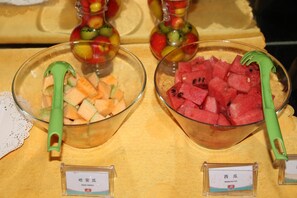 Deux saladiers remplis de fruits, l’un contenant du melon et l’autre de la pastèque, sont posés sur une table recouverte d’une nappe jaune.