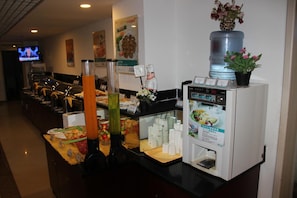 A buffet area with a coffee machine, a water dispenser, and a television displaying a news program. - Jinjiang Inn Beijing Yizhuang Economic & Technical (Beijing)