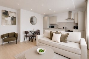 Ein modernes Wohnzimmer mit Sofa, Couchtisch und Essbereich mit Stühlen.