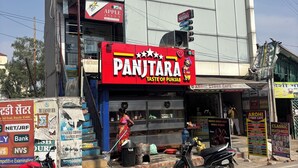 Um edifício com uma placa indicando 'Hotel Tuk Tuk Palace' e um restaurante chamado 'Panjitra Taste of Punjab'.
