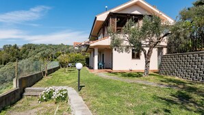 A two-story house with a balcony, a paved driveway, and a stone wall. - A welcoming and spacious 100 square meters apartment, perfect for six people, located on the ground floor of a complex of terraced houses.The property is located in San Lorenzo al Mare, in an extremely quiet area surrounded by nature: the typical Liguria (San Lorenzo al Mare)