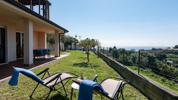 A patio with outdoor furniture, a view of the sea, and a building with a balcony. - A welcoming and spacious 100 square meters apartment, perfect for six people, located on the ground floor of a complex of terraced houses.The property is located in San Lorenzo al Mare, in an extremely quiet area surrounded by nature: the typical Liguria (San Lorenzo al Mare)