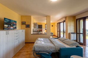 Ein Hotelzimmer mit Bett, Fernseher, Küchenzeile und Blick ins Freie.