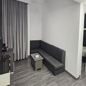 A modern room with a grey sofa, a small table, and a curtain. - 3BR Urban Oasis Apartment Royal Tulip Retreat (Sharjah)