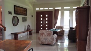 A spacious living area with a dining table, sofa, and a large wooden cabinet. - Dagope Homestay (Lembang)
