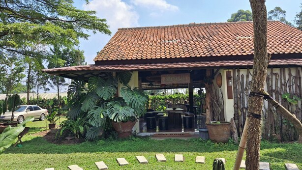 A rustic building with a tiled roof, surrounded by lush greenery and a car parked nearby. - Dagope Homestay (Lembang)