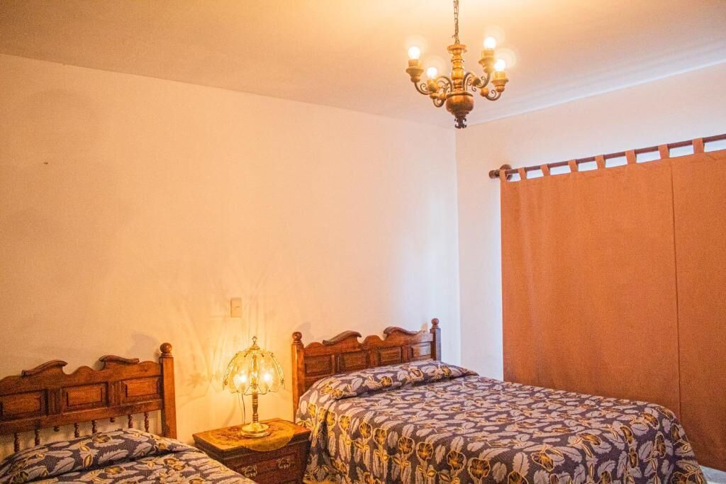 A bedroom with a wooden bed, a nightstand with a lamp, and a chandelier.